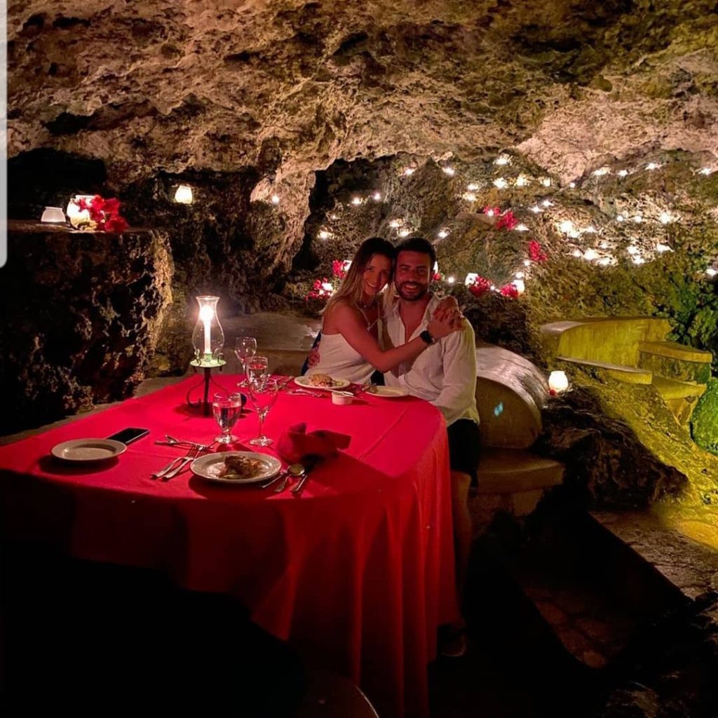 Happy couple on a romantic dinner date at The Caves in Negril, showcasing Jamaican Tours and Excursions for Couples.