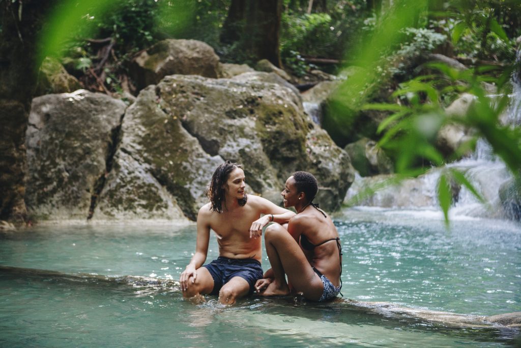  A couple enjoying a serene moment in a natural pool, with a waterfall in the background